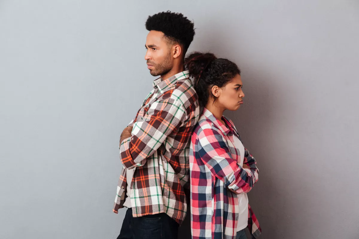 Couple in conflict, standing back-to-back in plaid, showcasing relationship tension.