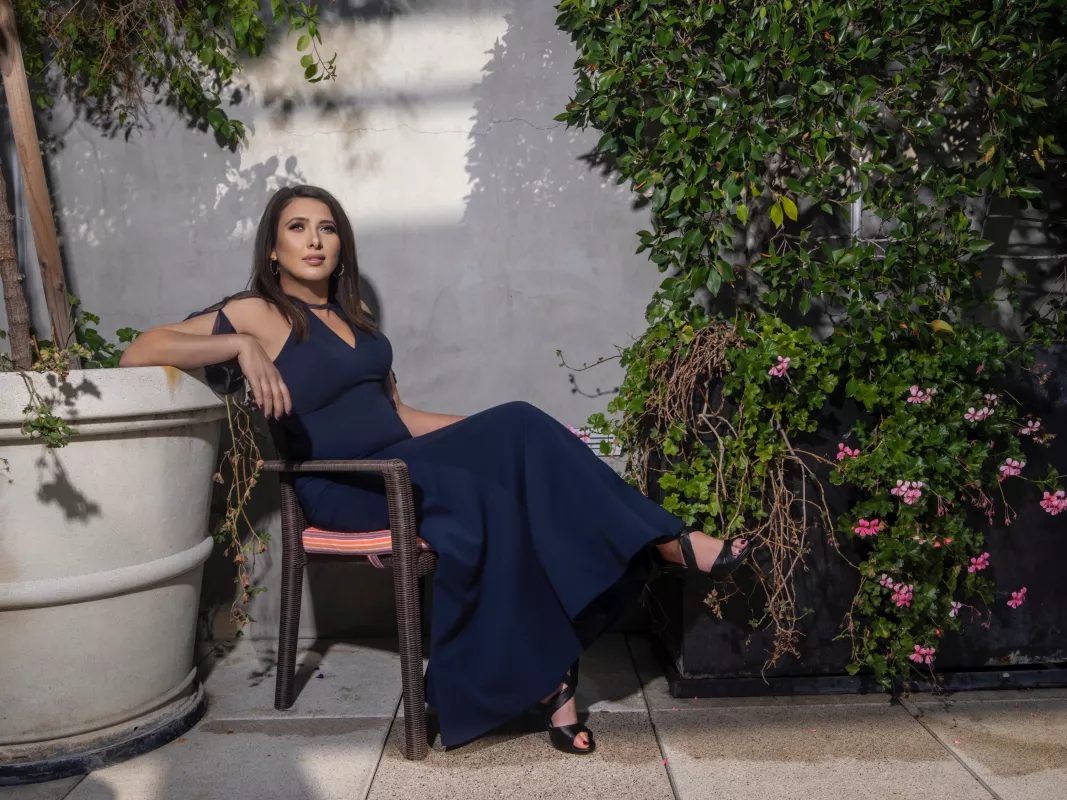 Elegant blue dress portrait in a serene garden setting with lush foliage.