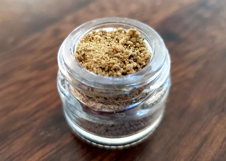 Organic ground spice in jar, artisanal seasoning on rustic wood backdrop.