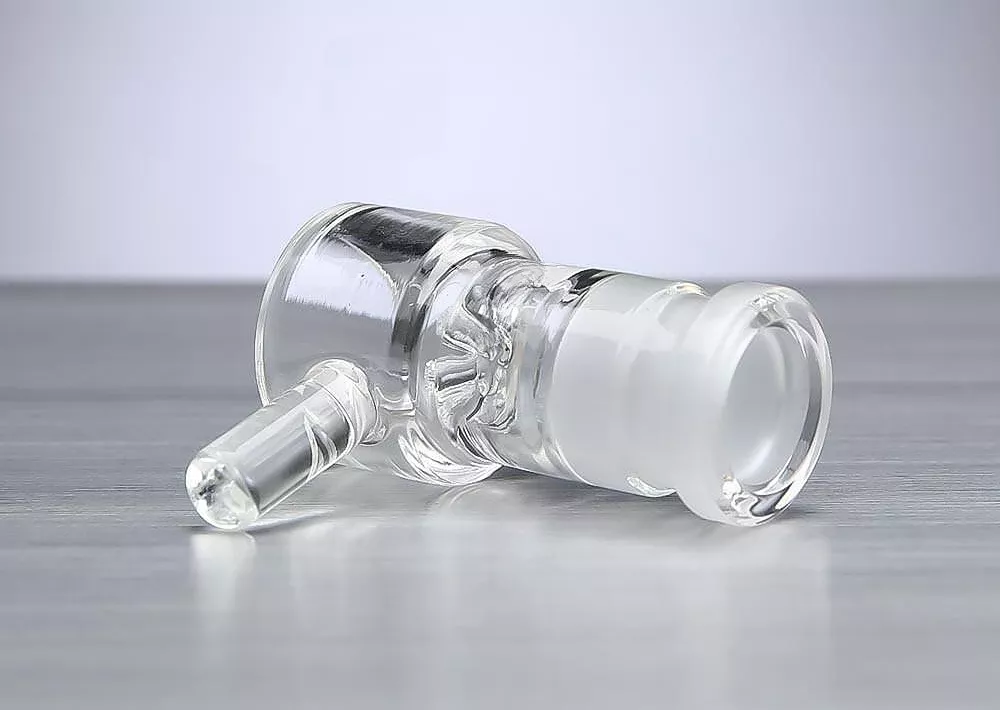 Clear glass bong component with downstem on reflective surface.