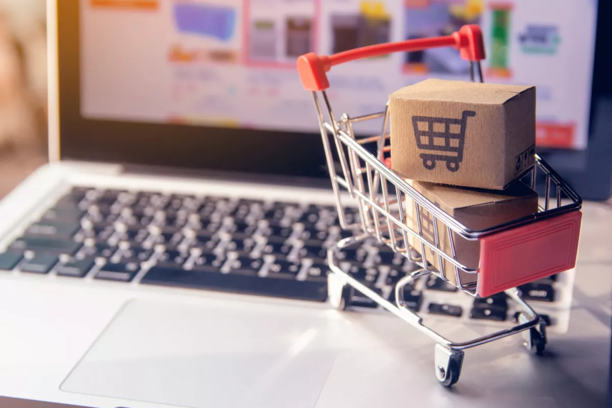 Mini shopping cart on laptop keyboard representing e-commerce and online shopping.