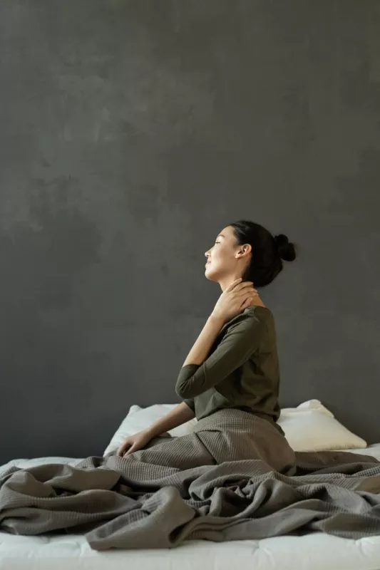 Person in green shirt finds peace with CBD or THC on an unmade bed.