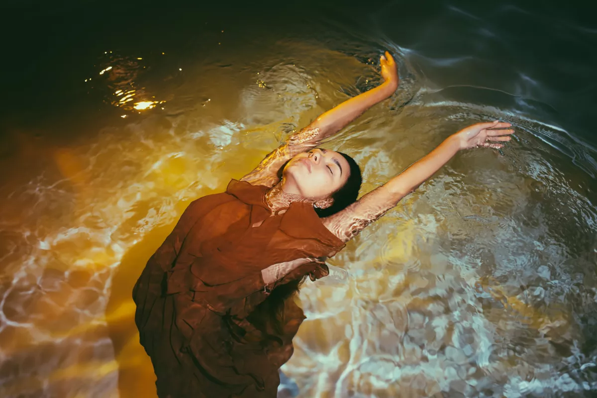 Person in peaceful floatation on water during golden hour, symbolizing tranquility and relief.