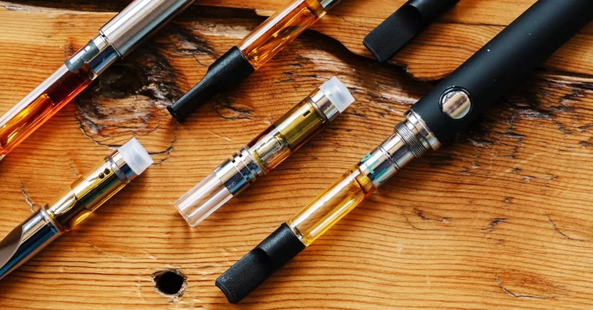 Collection of various vape pens on rustic wooden surface.