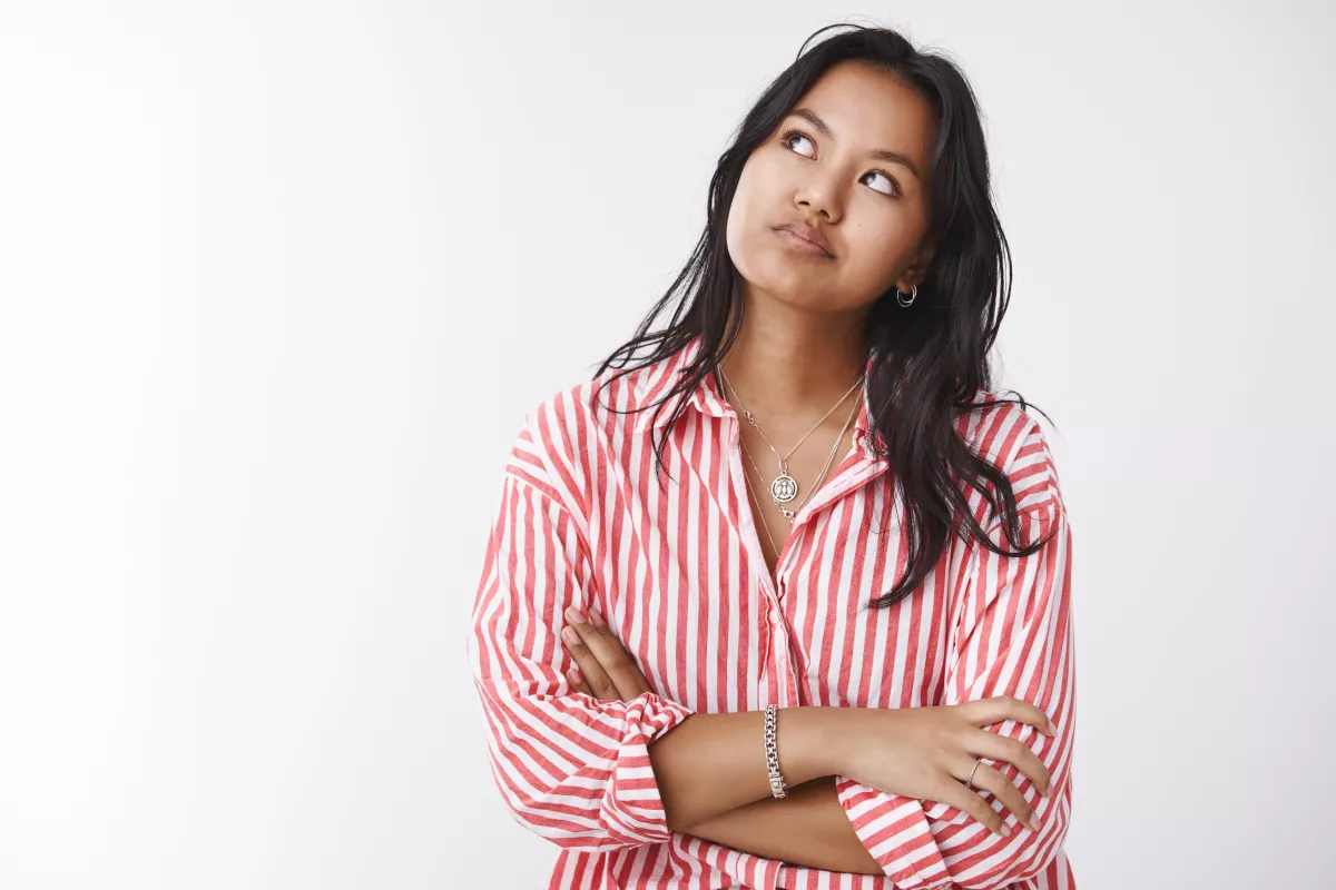 Contemplative woman in striped shirt, reflective pose, bright background.