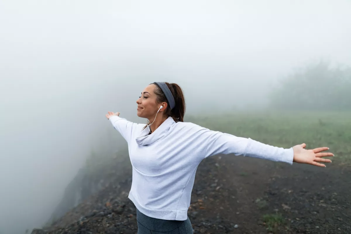 Woman in white enjoying serene, foggy solitude outdoors while exercising.