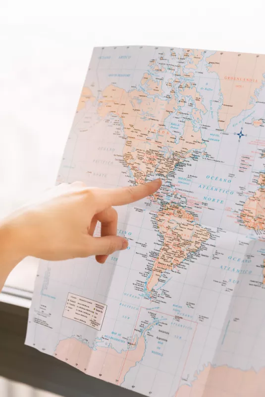 Hand pointing to Eastern North America on a Spanish world map.