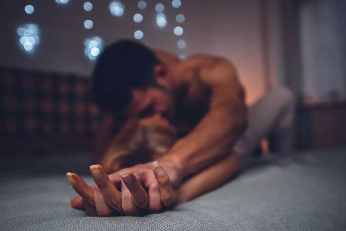 Man in tranquil yoga Childs Pose on mat in dimly lit room for evening relaxation.