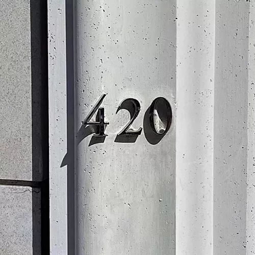 Modern concrete column with metallic 420 address numbers.