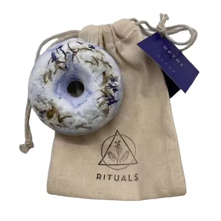 Handmade bath bomb with dried botanicals and fabric pouch.