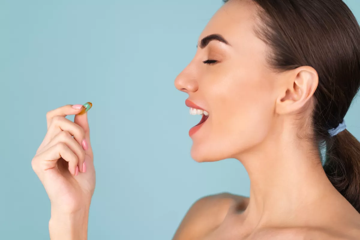 Woman happily taking fish oil supplement for wellness.
