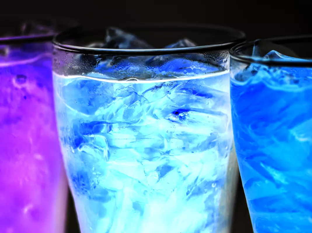 Iced CBD drinks in gradient-hued glasses with vibrant blue and purple tones on dark background.