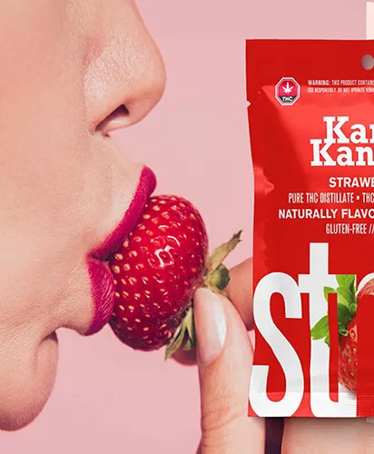 Red lips biting strawberry with cannabis-infused edible package, Kan Kan THC distillate.