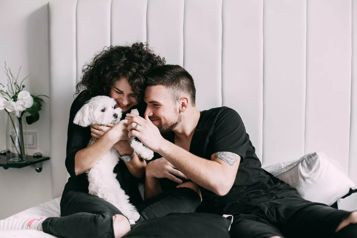 Couple in black enjoys a warm moment with white fluffy dog at home.