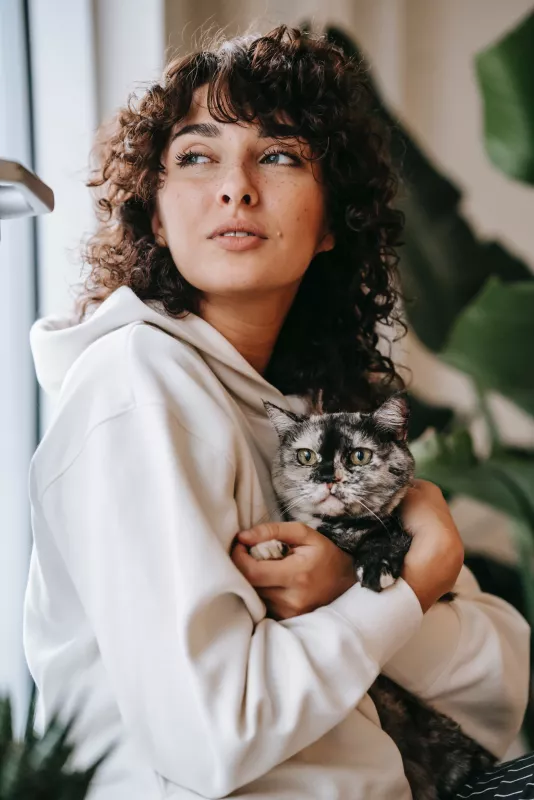 Woman cradles tabby cat, reflecting close companionship at home.