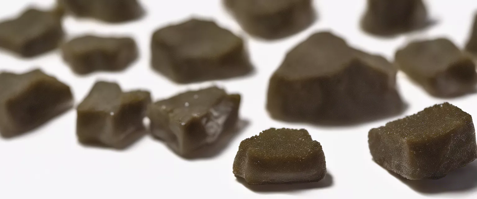 Close-up of glossy brown rock sugar crystals on white background.