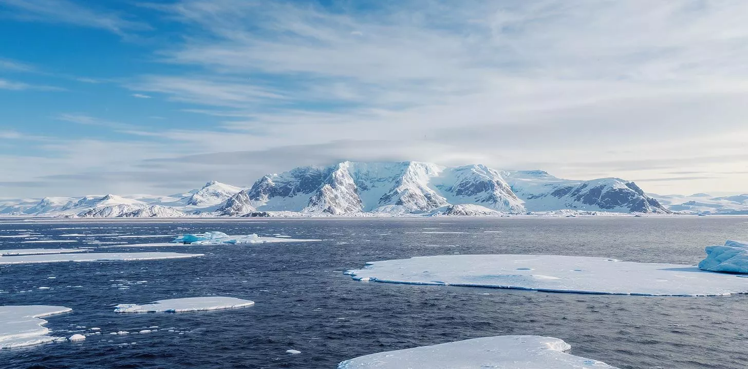 Majestic polar landscape with snow-capped mountains, ice floes, and a serene icy sea.