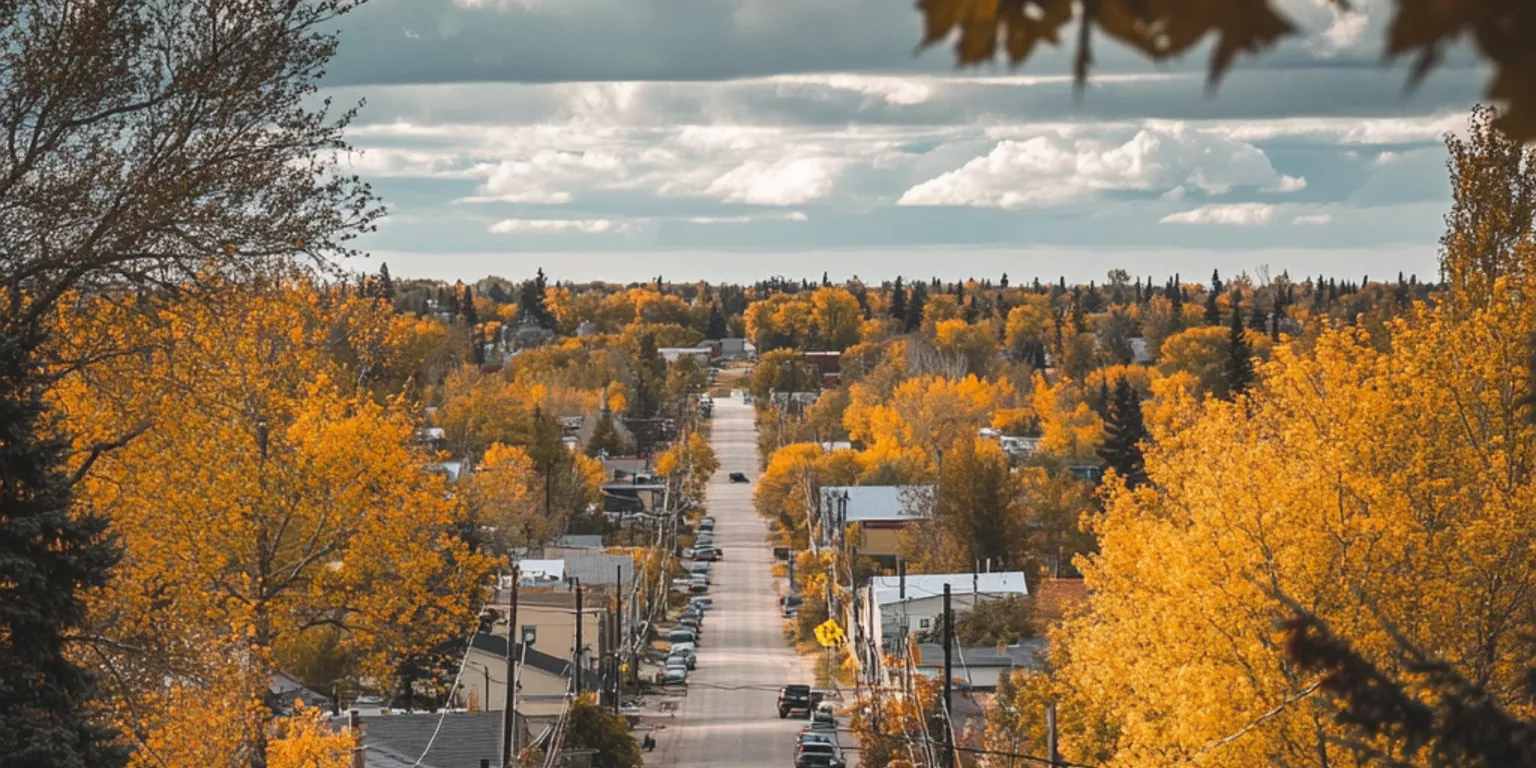 Autumn small-town road with colorful trees, quaint houses, and parked cars.