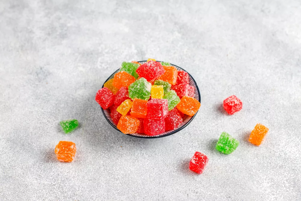 Colorful sugar-coated jelly candies in a dark bowl, assorted fruity flavors.