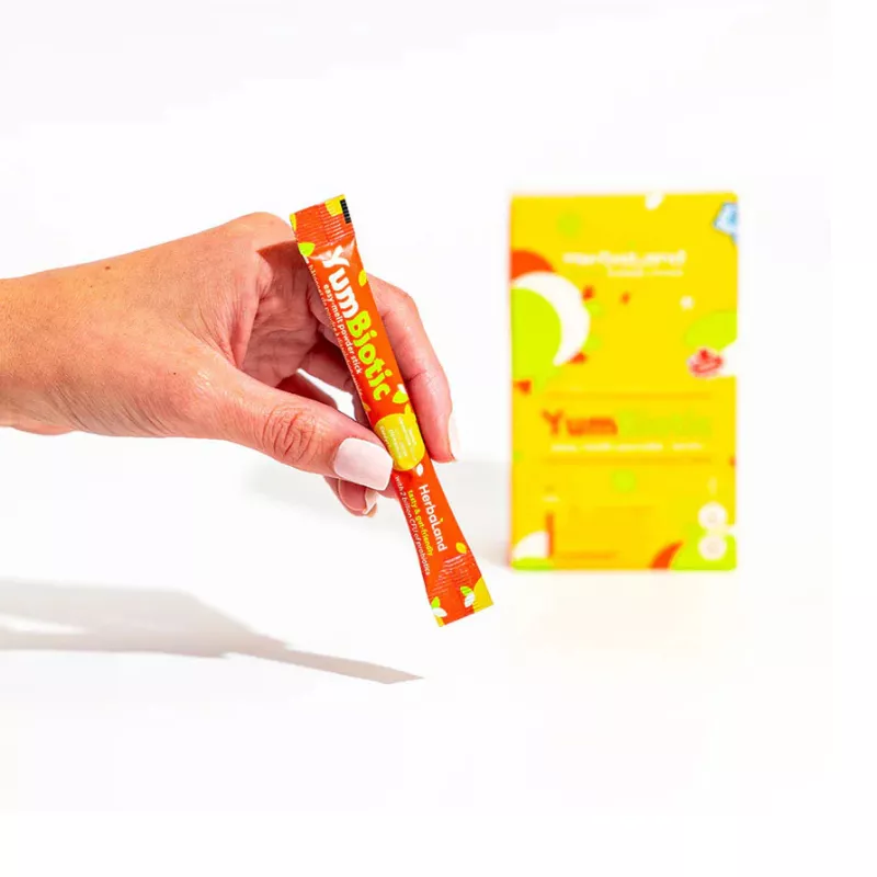 Hand holding YumBiotic probiotic supplement packet for digestive health, vibrant design.