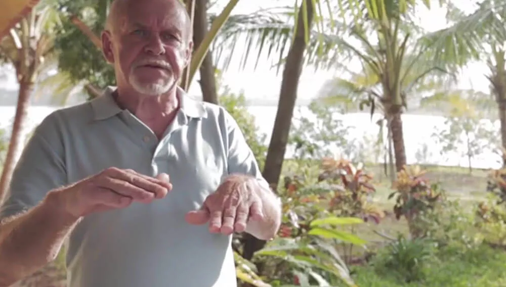 Man discussing Rick Simpson Oil benefits in tropical outdoor setting.