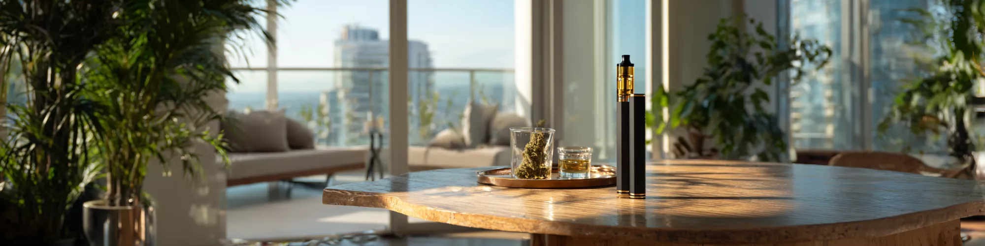 Modern interior with a wooden table, plants, a vape pen, and a glass.