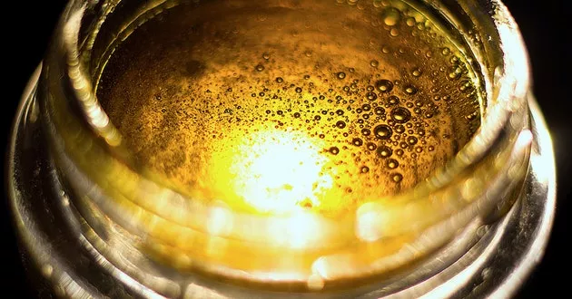 Close-up of golden bubbles in Rick Simpson Oil during carbonation process.