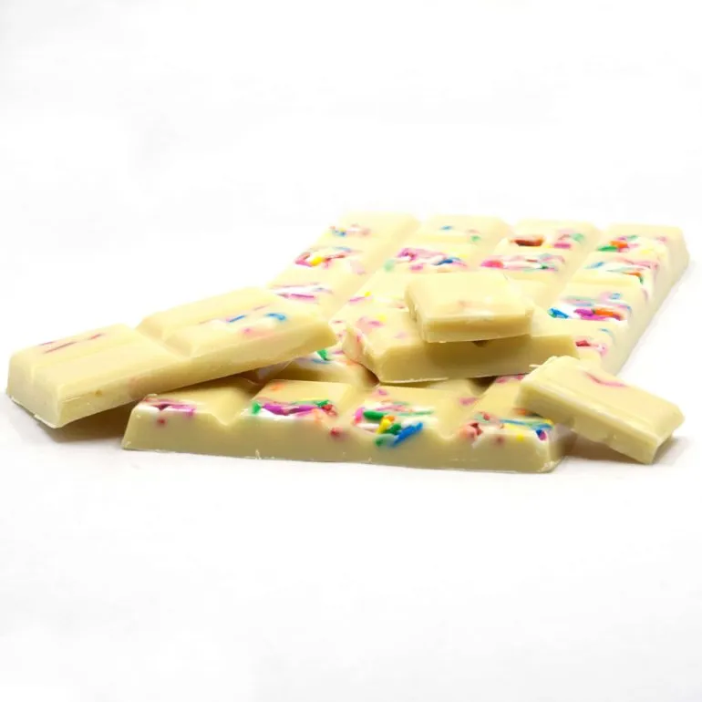 White chocolate bar with colorful sprinkles, broken into festive pieces for a birthday celebration treat.