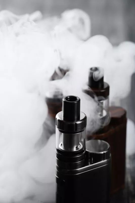 Sleek e-cigarettes amidst vapor, showcasing modern vaping device designs.