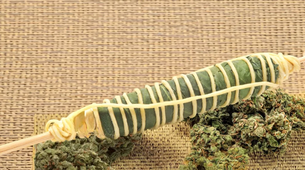 Handcrafted Thai stick and trichome-rich cannabis buds on burlap background.