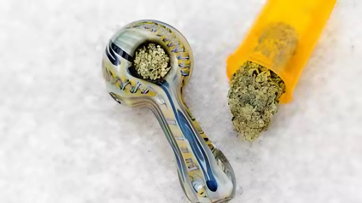 Yellow glass pipe with green substance on snowy background.